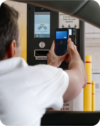 Vodič platí parkovné pomocou mobilného telefónu pri parkovacom automate.