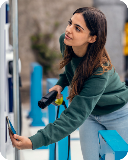Žena platí mobilom pri nabíjacej stanici pre elektromobily.